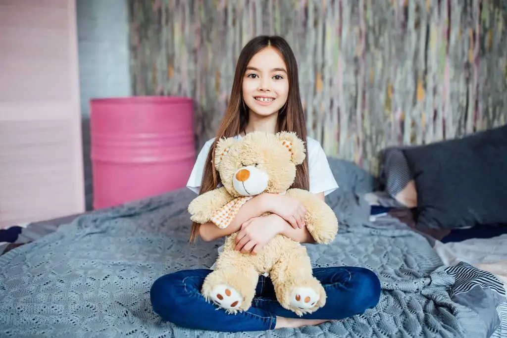 Criança feliz, sorrindo, segurando um urso de pelúcia