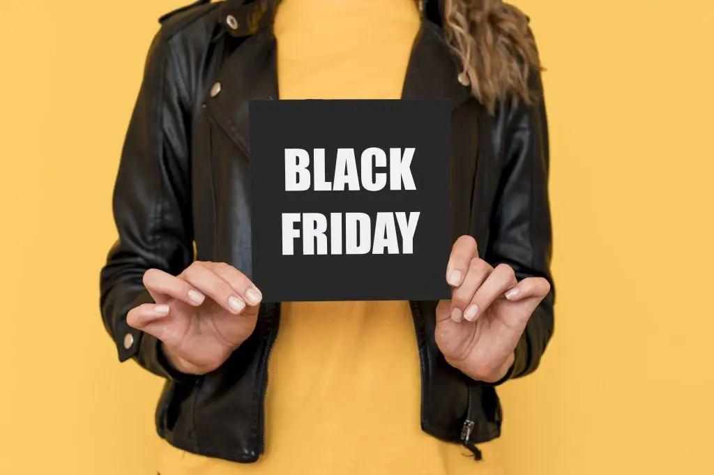 Fundo amarelo, mulher segurando placa preta escrito "black friday"