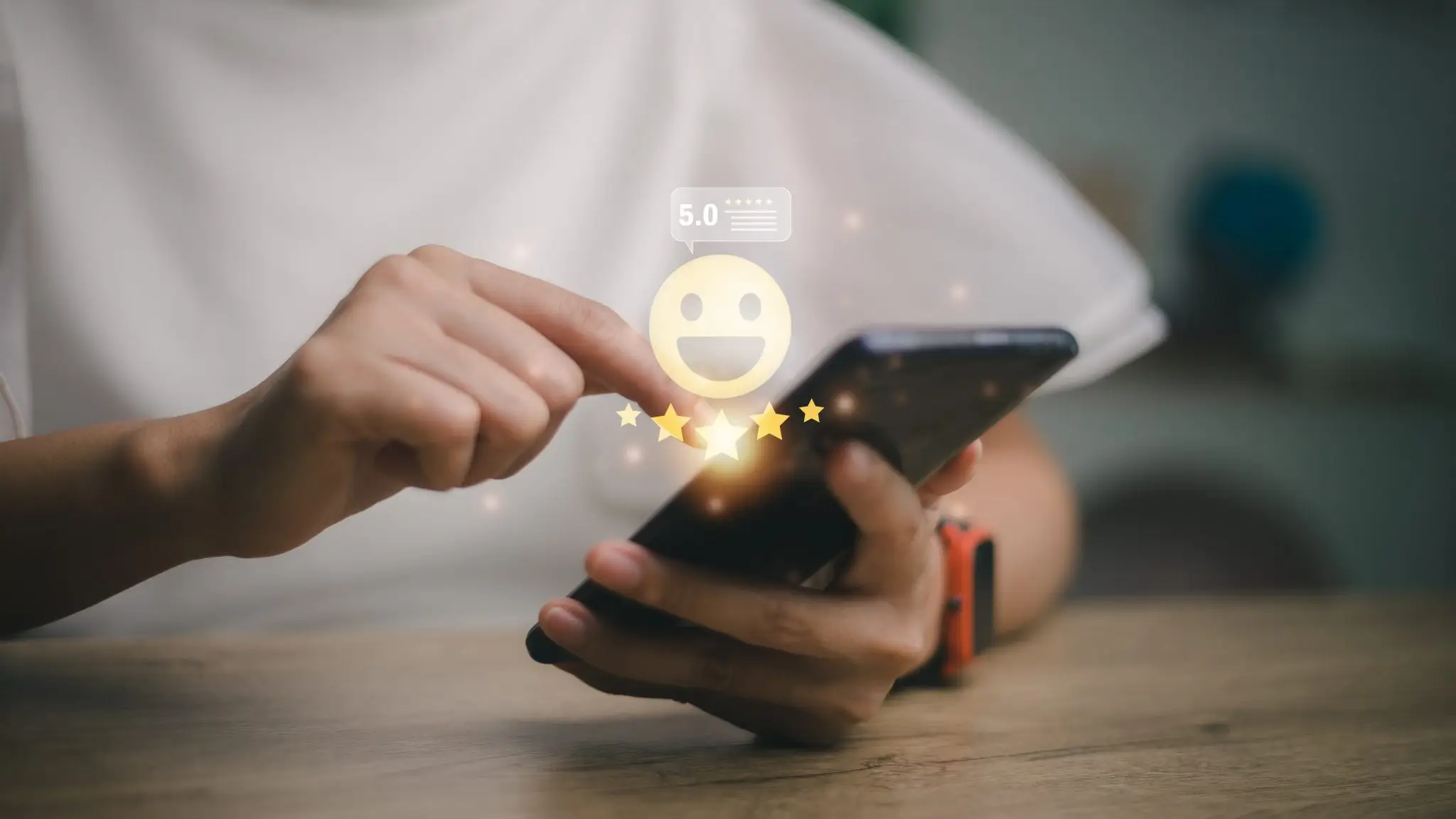 Descrição de imagem em português: Uma pessoa interagindo com um smartphone, tocando em uma avaliação de cinco estrelas que aparece sobre a tela junto a um emoji sorridente e o texto "5.0"